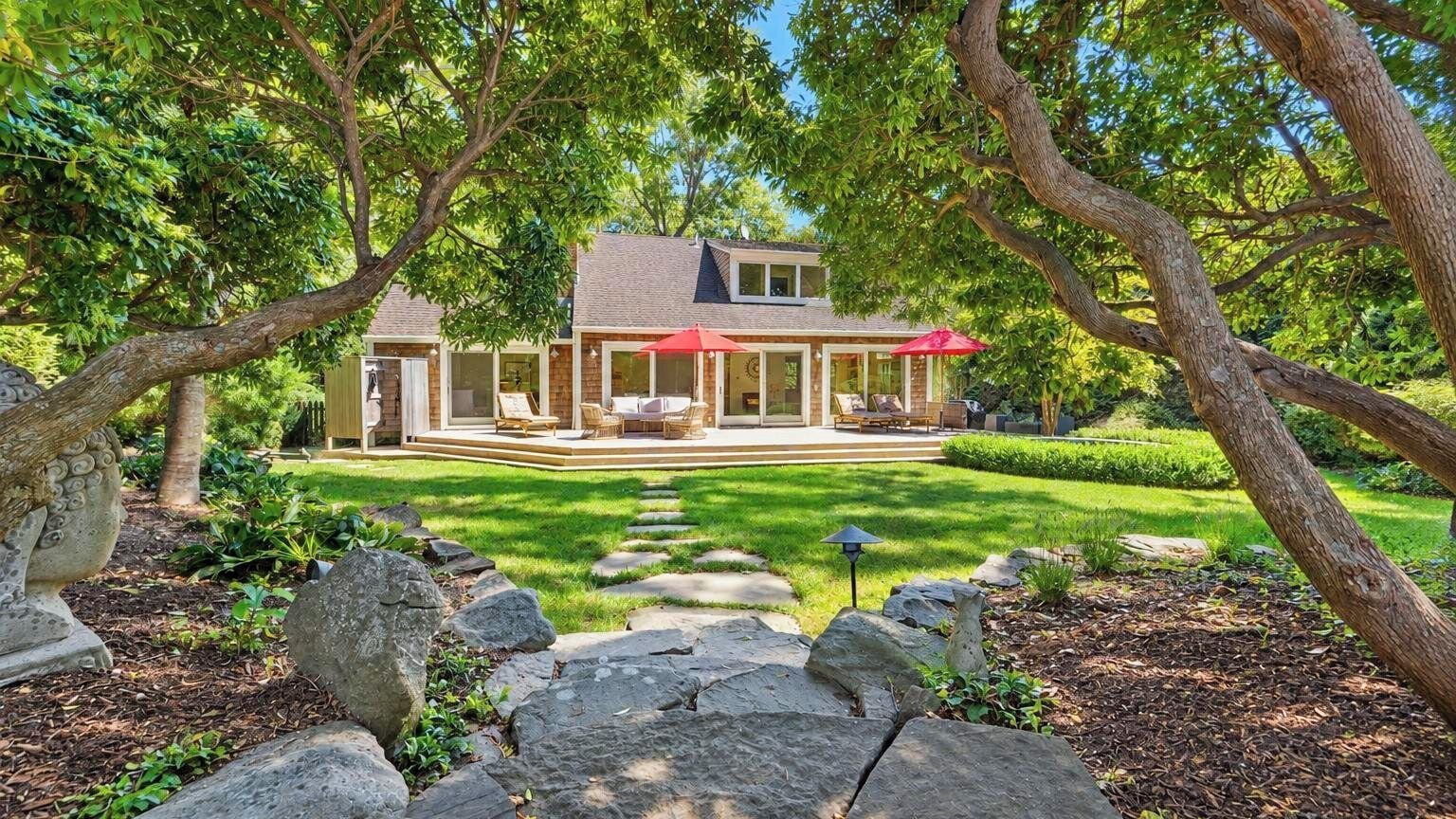 A house with a covered patio, a lawn, and a stone pathway leading to the entrance.