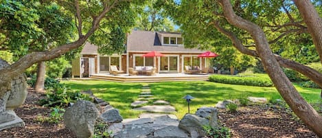 A house with a covered patio, a lawn, and a stone pathway leading to the entrance.