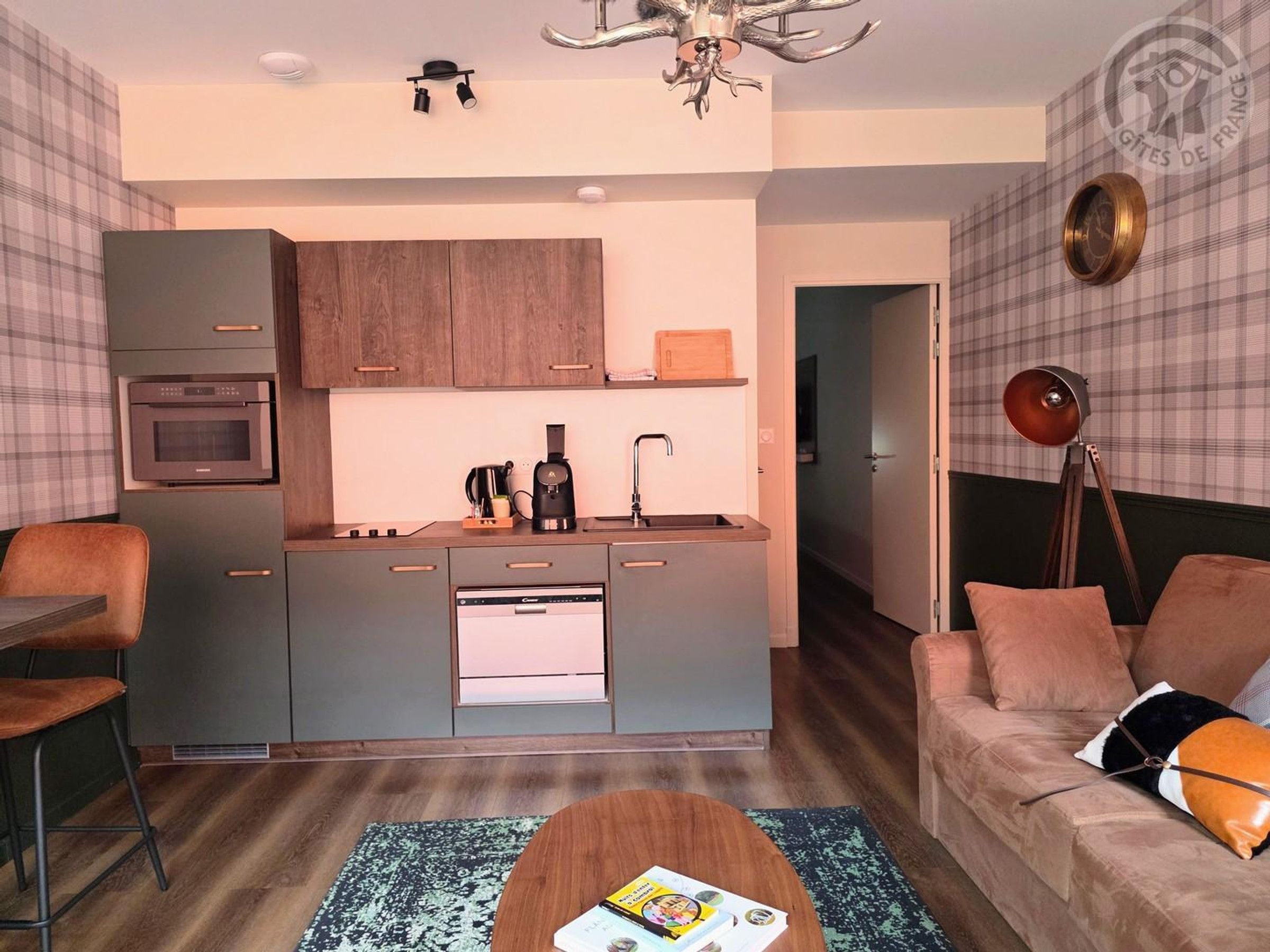 A modern living room with a sofa, a coffee table, and a kitchen area with a microwave and coffee maker.
