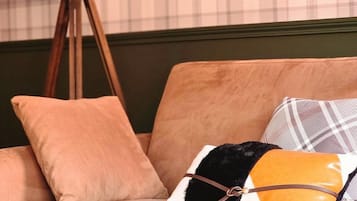 A sofa with multiple cushions in a room with a plaid wallpaper background.