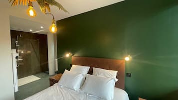 A hotel room with a bed, a shower, and a green wall.