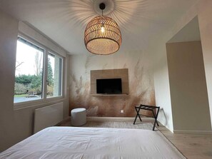 A bedroom with a large bed, a television mounted on the wall, a window, and a hanging light fixture. - Modern and spacious apartment - 15 guests (NIERGNIES)