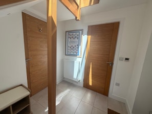 A hallway with two wooden doors, a radiator, and a framed emblem on the wall. - The Scholars Nest Luxury Loft Gym Parking WiFi (Cambridge)