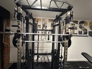 A gym with a squat rack, barbell, and weight plates. - The Scholars Nest Luxury Loft Gym Parking WiFi (Cambridge)