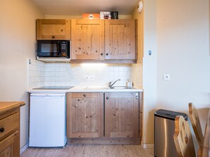 Cozinha compacta com armários de madeira, micro-ondas, pia e lava-louças.