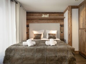 A bedroom with a wooden headboard, a large bed with white linens, and a fluffy rug. - Mountain chalet ski-in/ski-out - 8 guests (Courchevel)
