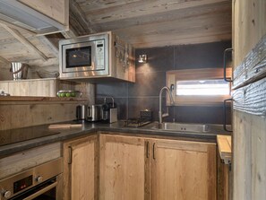 A compact kitchen with a built-in microwave, stainless steel sink, and wooden cabinetry. - Mountain chalet ski-in/ski-out - 8 guests (Courchevel)