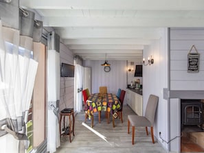 Un comedor con mesa de madera, sillas coloridas, televisor y chimenea.