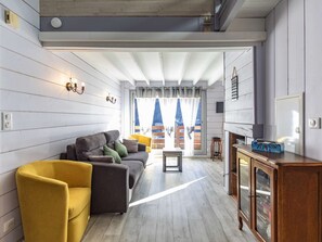 A modern living room with a sofa, a yellow armchair, and a wooden cabinet. - Charming apartment with terrace - 4 guests (Cauterets)