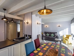 A modern kitchen with a central island, a dining area with colorful tablecloth, and a living room with a sofa and chairs. - Charming apartment with terrace - 4 guests (Cauterets)