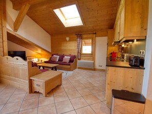 A cozy wooden interior with a sofa, a coffee table, a TV, and a kitchen area. - Cozy duplex with parking - 8 guests (Samoëns)