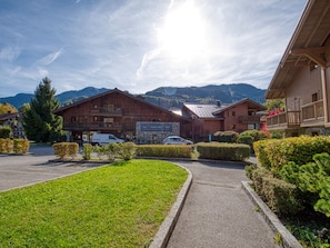 A wooden building with a sign indicating a restaurant, surrounded by well-maintained hedges and a clear sky. - Cozy duplex with parking - 8 guests (Samoëns)