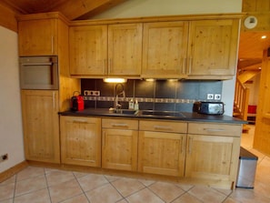 A kitchen with wooden cabinets, a stainless steel sink, a toaster, and a red kettle. - Cozy duplex with parking - 8 guests (Samoëns)