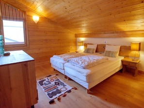 A wooden cabin bedroom with a double bed, bedside lamps, a wooden desk, and a window with blinds. - Cozy duplex with parking - 8 guests (Samoëns)