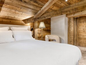 A bedroom with a large bed, a nightstand, a lamp, and a chair. - Chalet at the foot of the slopes with sauna - 15 guests (Les Saisies)