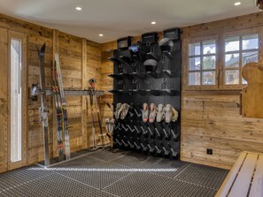 Une salle de rangement pour les skis, où les skis et les chaussures de ski sont rangés de manière ordonnée sur des étagères, ainsi qu’un télésiège et un intérieur en bois.