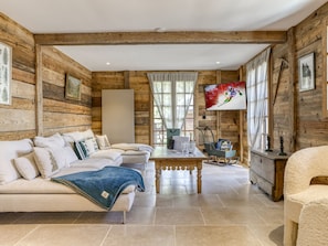 A log cabin interior with a sofa set, a dining table, and a TV mounted on the wall. - Chalet at the foot of the slopes with sauna - 15 guests (Les Saisies)