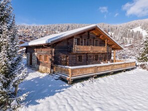 A wooden chalet with a balcony, surrounded by snow-covered trees and a mountainous backdrop. - Chalet at the foot of the slopes with sauna - 15 guests (Les Saisies)