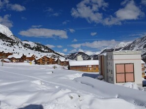 A snow-covered mountain area with wooden buildings and a modern structure. - Central apartment - 6 guests (Montgenèvre)