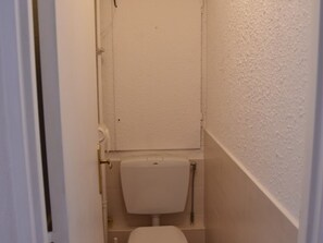 A narrow, white-walled bathroom with a toilet and a door. - Central apartment - 6 guests (Montgenèvre)