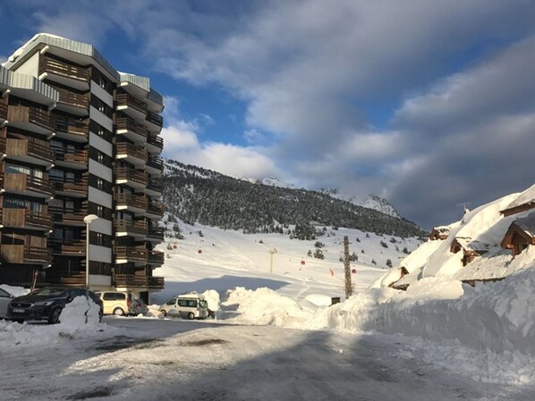 A multi-story building with balconies, a snowy landscape, and a ski slope in the background. - Apartment balcony mountain view - 4 guests (Montgenèvre)