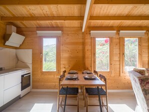 Ein Holzinterieur mit Esstisch, Stühlen, einer Couch und einer Küchenzeile.
