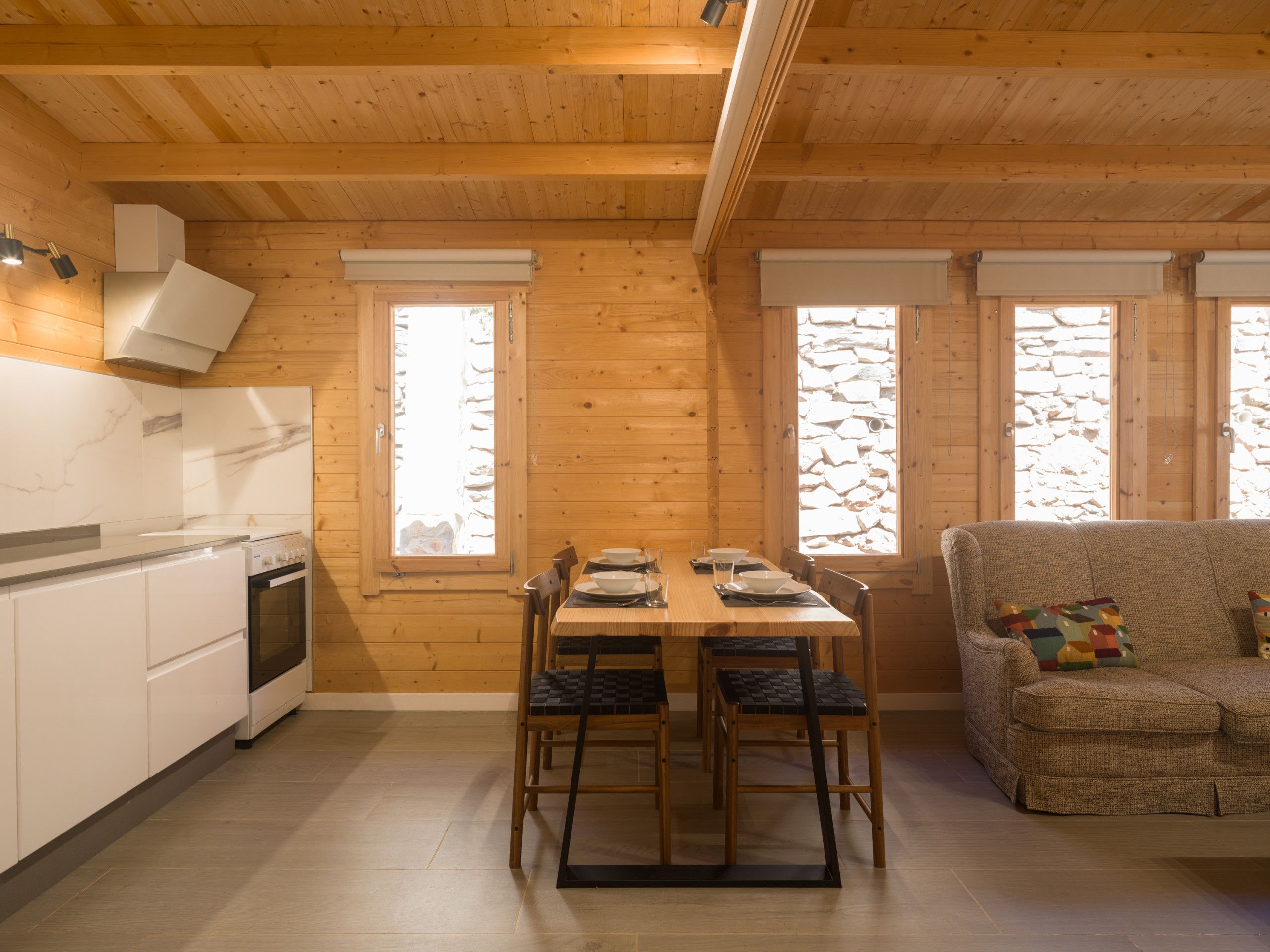 Een houten interieur met een keuken, een eettafel en een bank.