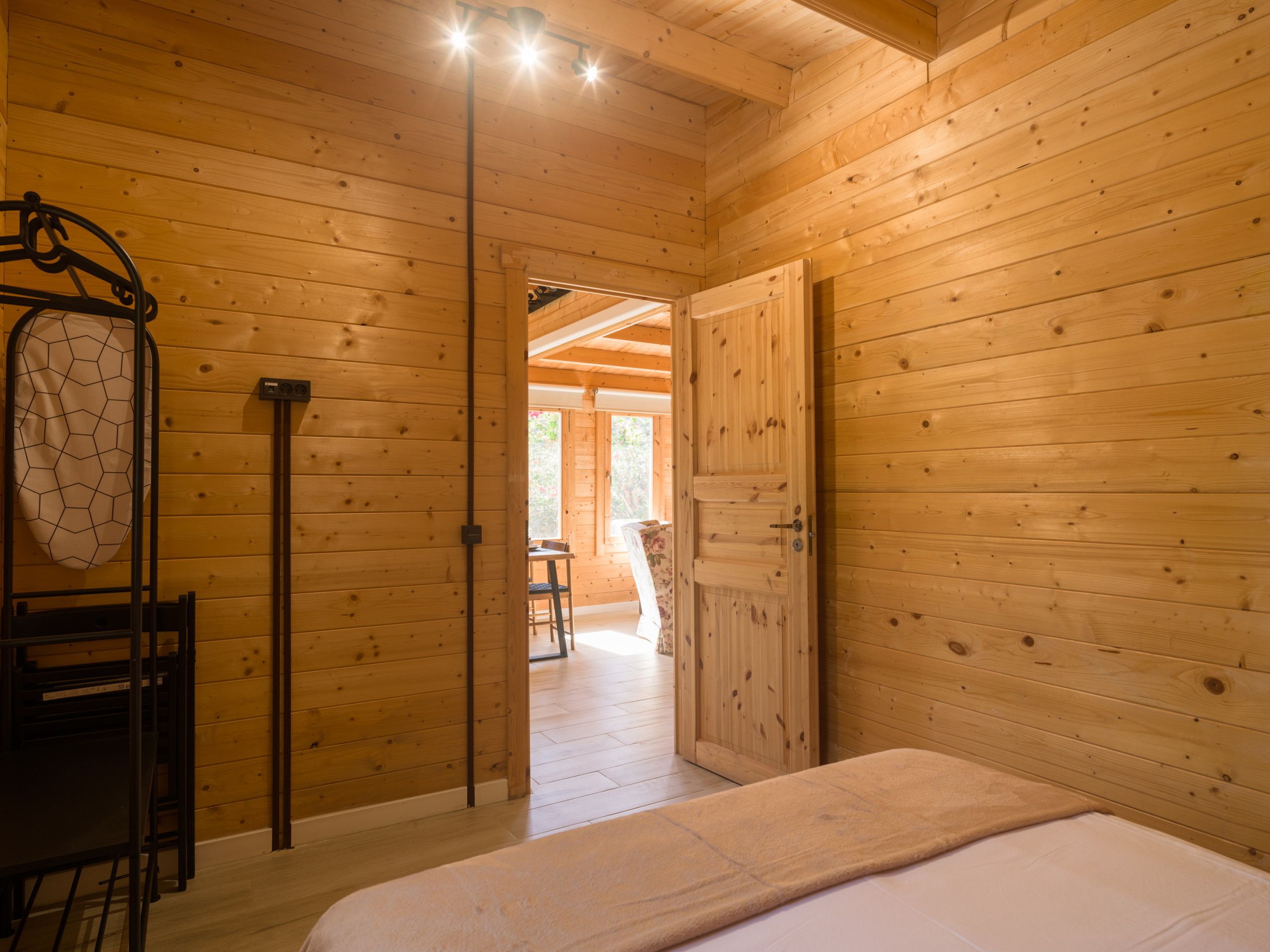 A wooden interior with a bed, a chair, and a table.