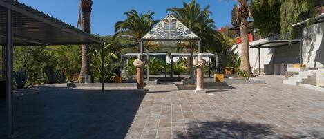 A courtyard with a gazebo, palm trees, and a statue.