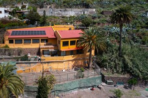 A yellow building with a red roof, solar panels, and a fenced area with a palm tree. - Rural Refuge by CanariasGetaway (Telde)