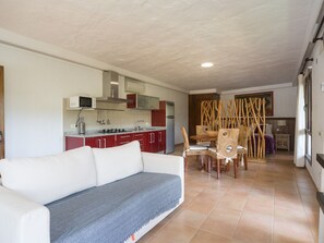 A modern living room with a sofa, a dining area with chairs, a kitchen with red cabinets, and a wooden partition. - German Lofts by CanariasGetaway (Telde)