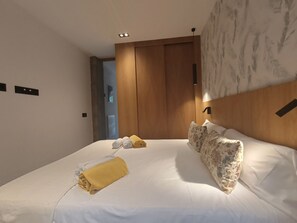 Ein Hotelzimmer mit einem großen Bett, einem hölzernen Kopfteil und einer wandmontierten Leuchte.