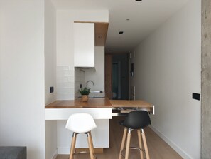 Eine moderne Küche mit weißen Schränken, einer Holz Arbeitsplatte und zwei Barhocker.