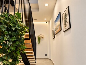 A modern interior with a staircase, wall-mounted artwork, and a potted plant. - Costa Suites 49 1 I By CanariasGetaway (Las Palmas de Gran Canaria)