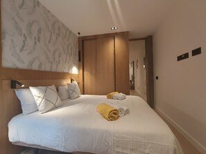 A hotel room with a large bed, a wooden headboard, a wall-mounted light, and a door with a mirror. - Costa Suites 49 1 I By CanariasGetaway (Las Palmas de Gran Canaria)