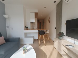 A modern living room with a sofa, a coffee table with a plant, a dining area with a table and chairs, and a kitchen with a countertop and cabinets. - Costa Suites 49 1 D by CanariasGetaway (Las Palmas de Gran Canaria)