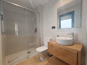 A modern bathroom with a glass-enclosed shower, a white toilet, and a wooden vanity with a sink. - Costa Suites 49 1 D by CanariasGetaway (Las Palmas de Gran Canaria)