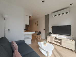 A modern living room with a sofa, a coffee table, a TV, and a dining area. - Costa Suites 49 1 D by CanariasGetaway (Las Palmas de Gran Canaria)