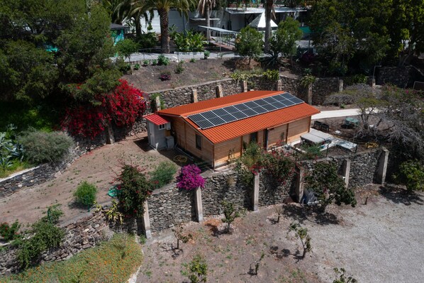A building with a red roof and solar panels, surrounded by various plants and trees. - Casa África Loft - Finca Cruz Mayor (Telde)