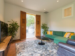 A living room with a green sofa, a coffee table, and two potted plants. - Casa África Loft - Finca Cruz Mayor (Telde)