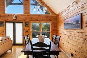 A wooden cabin interior with a dining table, chairs, a vase, and a framed picture. - God`s Promise | Cozy, Peaceful, Hot Tub, Fireplace (Sevierville)