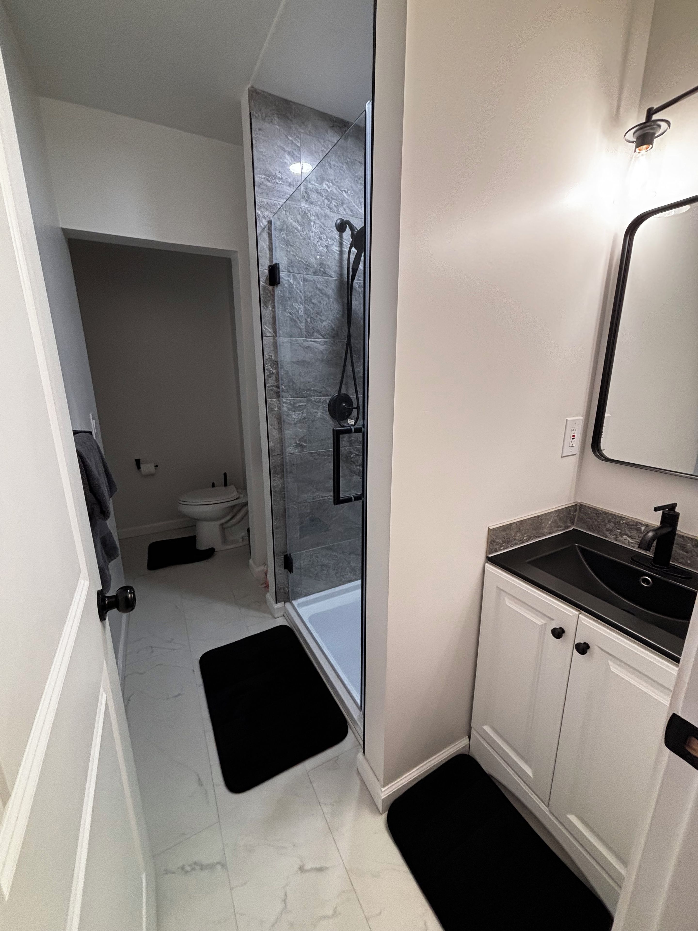 A bathroom with a glass-enclosed shower, a white sink, and a mirror.