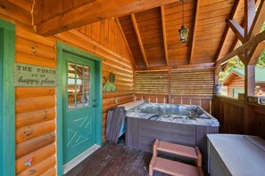 A wooden cabin with a hot tub, a green door, and a sign that reads 'THE PORCH IS MY happy place.' - Smokies Sunrise | Hot Tub, Fireplace & More! (Sevierville)