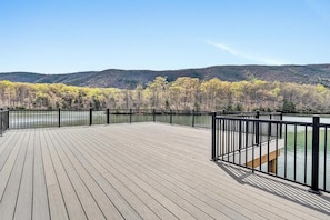 A wooden deck with a railing overlooking a body of water and forested hills. - Grand Cove Sanctuary (Smith Mountain Lake)