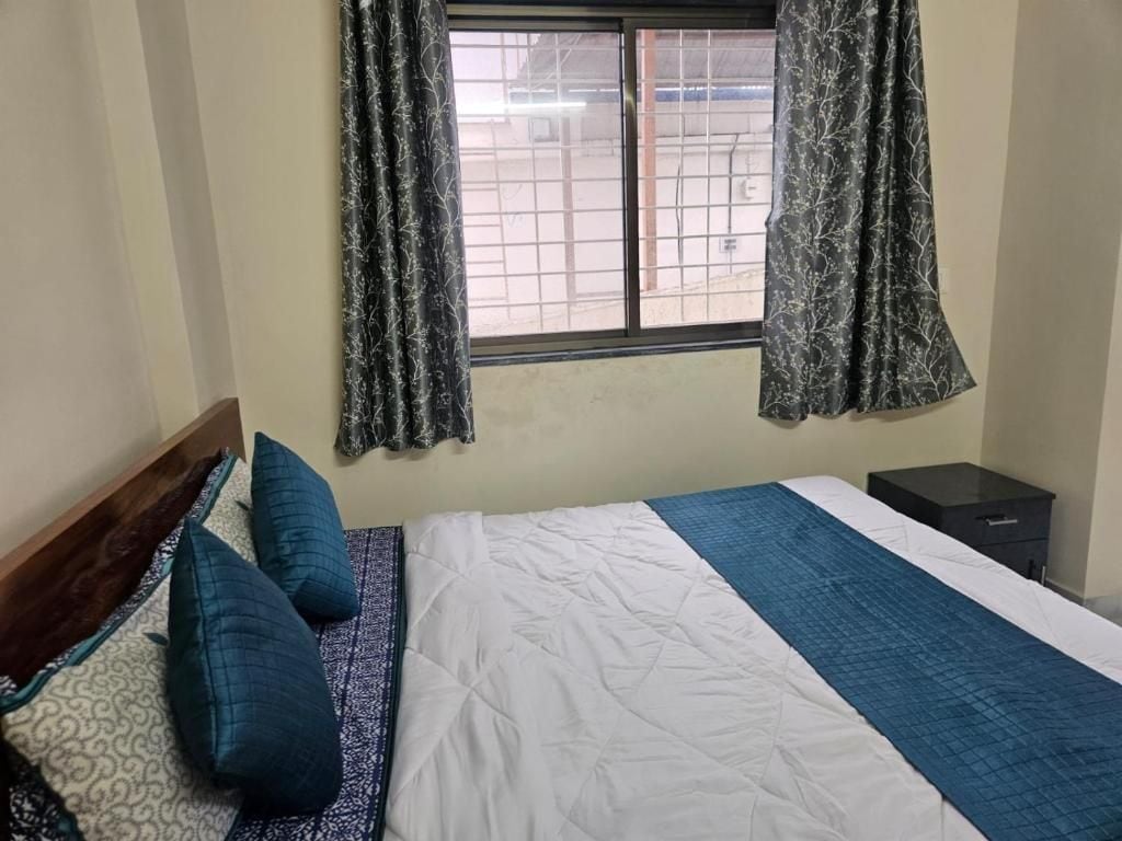 Quarto com cama, almofadas, mesa de cabeceira e janela com cortinas.
