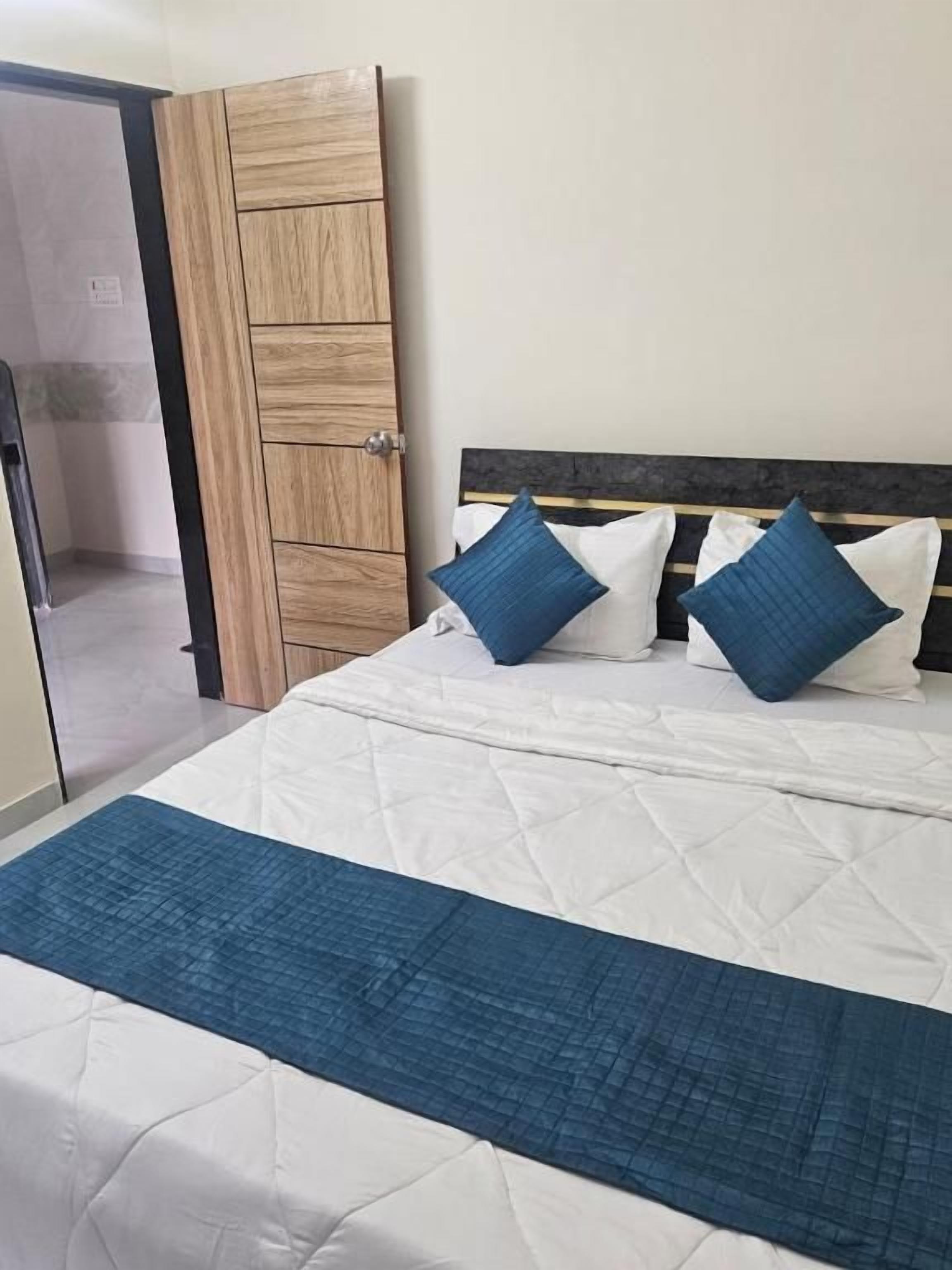 Un lit recouvert d’une couette blanche matelassée, avec deux oreillers bleus et un plaid bleu.