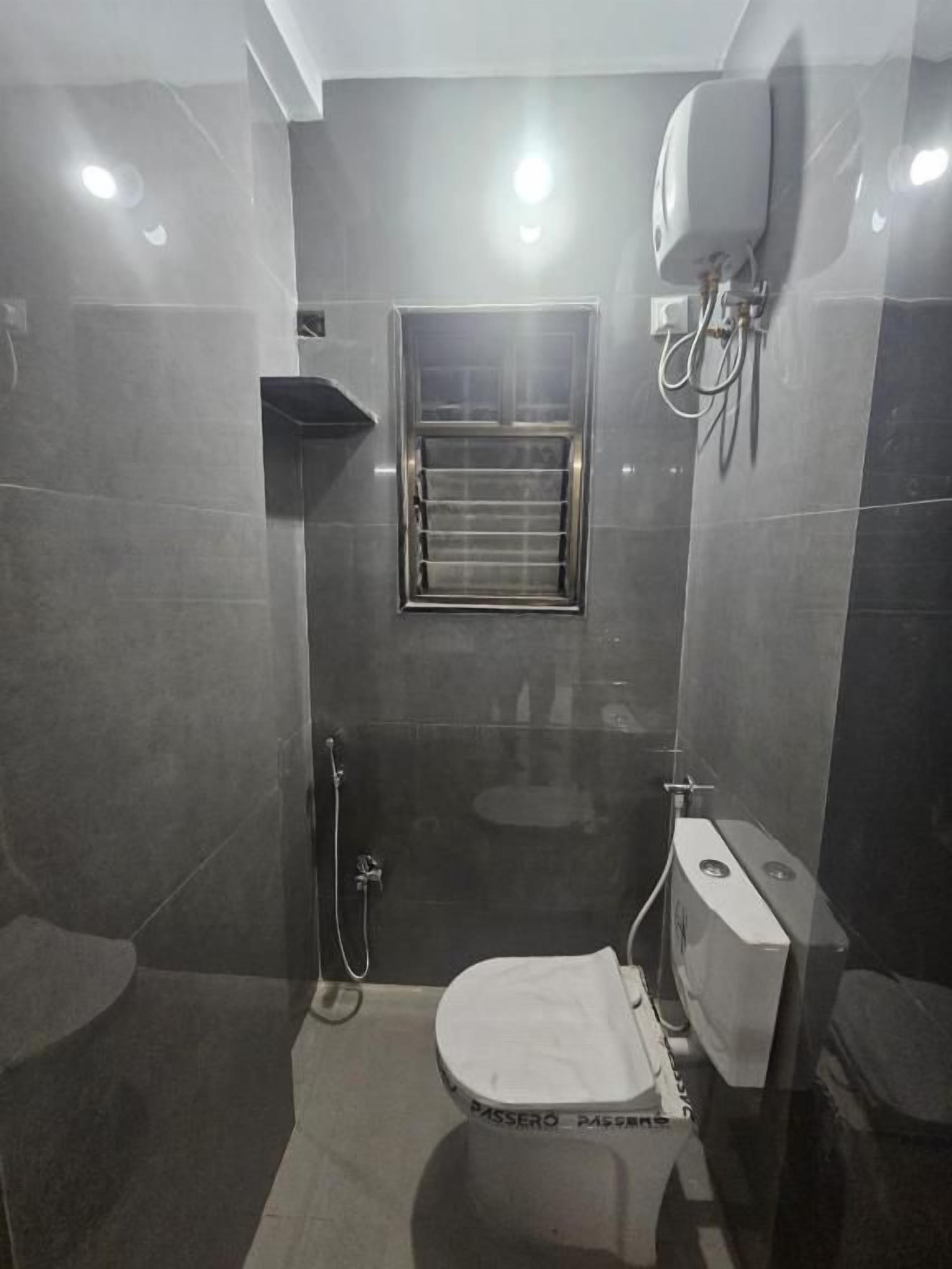 Une salle de bain équipée de toilettes, d’une douche et d’un sèche-mains.