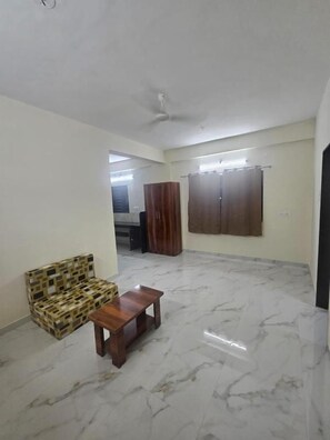 Amplia habitación con piso de mármol, un sofá, una mesa de madera y un ventilador de techo.