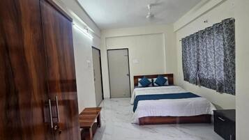 Une chambre à coucher comprenant un lit, une armoire, un banc et un ventilateur de plafond.