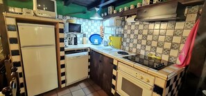 A compact kitchen with a refrigerator, microwave, coffee maker, and a stove. - Country House 'Menta y Canela' with Mountain Views, Private Terrace and Barbecue (Tórtoles)